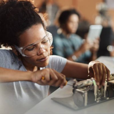 African American student of science repairing an electrical component in a lab.
